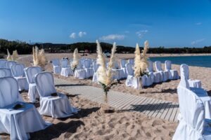 weiß bezogene Stühle, Pampasgras und Sand sind die Elemente für diese Strandhochzeit - meer sardinien urlaub